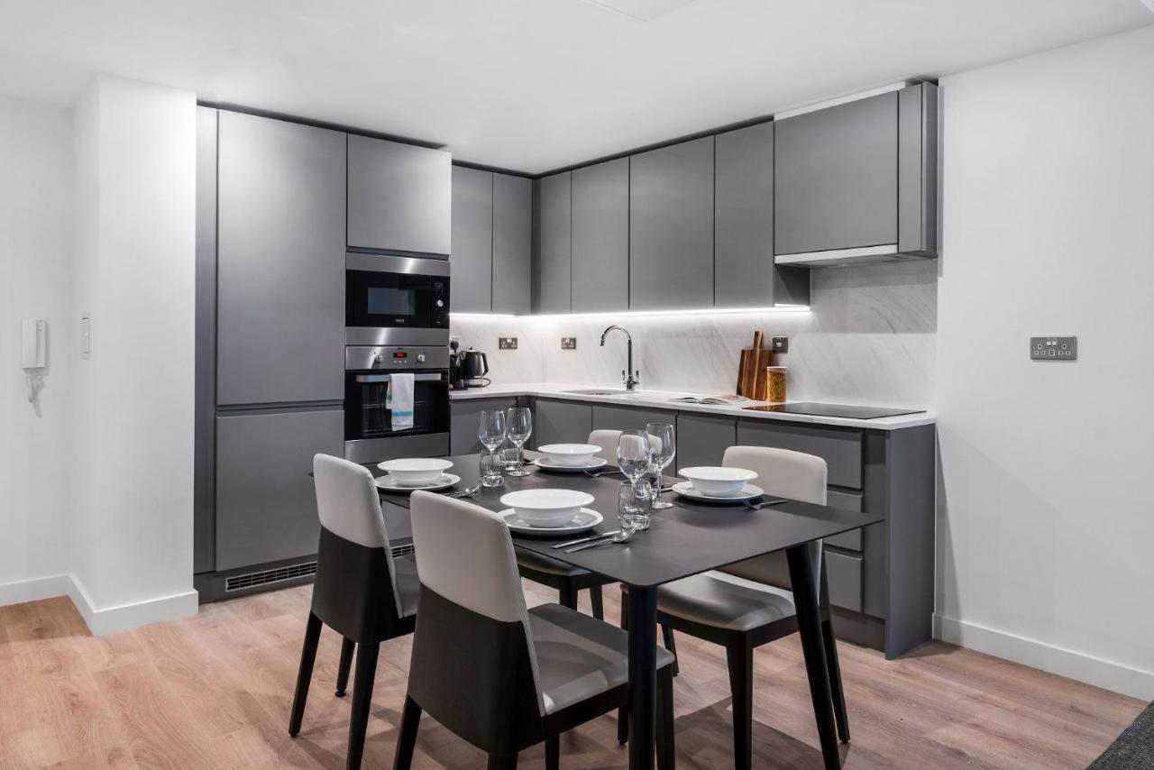 Citysuites 2 Aparthotel Manchester Bagian luar foto The photo shows a modern kitchen and dining area. The kitchen features sleek, gray cabinetry and a countertop that complements the overall aesthetic. There are built-in appliances, including an oven and refrigerator, arranged neatly. Next to the kitc