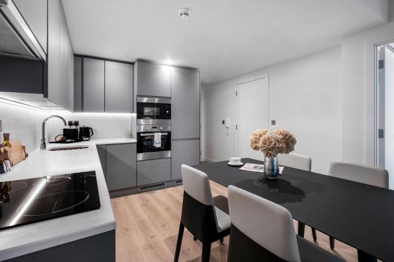 Citysuites 2 Aparthotel Manchester Bagian luar foto The photo shows a modern kitchen and dining area. The kitchen features sleek gray cabinets, a countertop with an embedded cooktop, and built-in appliances, including an oven and microwave. There’s a small coffee maker on the counter. Adjacent to the 