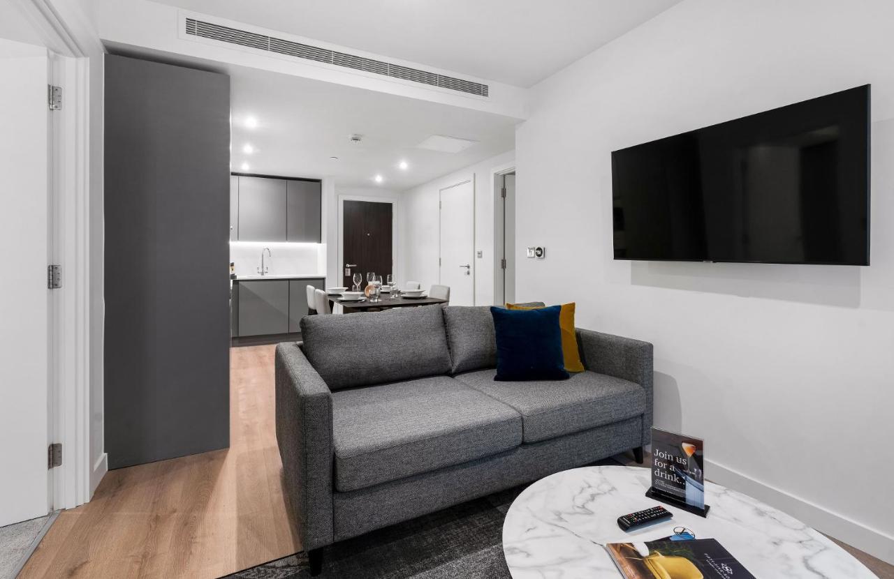 Citysuites 2 Aparthotel Manchester Bagian luar foto The photo shows a modern living space that includes a gray sofa with colorful cushions, a round marble coffee table, and a flat-screen TV mounted on the wall. In the background, there is a kitchen area featuring sleek cabinets. The flooring is light 