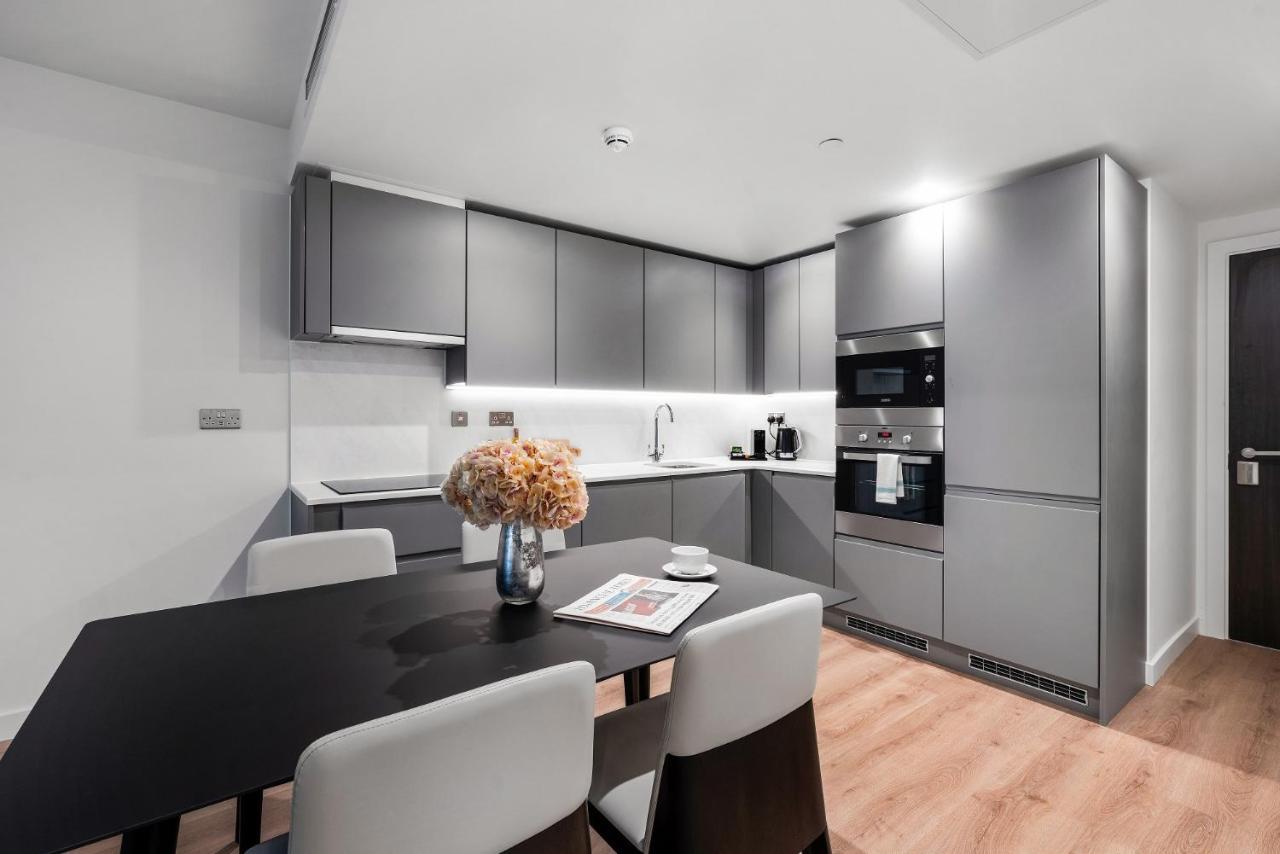 Citysuites 2 Aparthotel Manchester Bagian luar foto The photo shows a modern kitchen space. It features sleek, gray cabinetry with a minimalist design. There is a countertop with a sink, and appliances including an oven and a coffee maker. A dining table is positioned near the kitchen area, accompanie