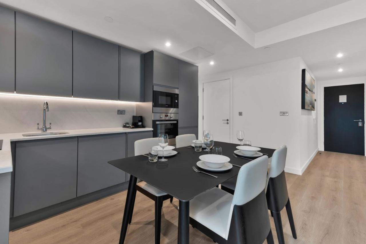 Citysuites 2 Aparthotel Manchester Bagian luar foto The photo shows a modern kitchen and dining area. There are sleek gray cabinetry and countertops, with a built-in oven and microwave. The kitchen is well-lit, featuring under-cabinet lighting that adds to the contemporary feel. In the dining area, th