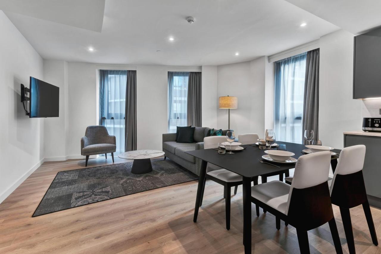 Citysuites 2 Aparthotel Manchester Bagian luar foto The photo shows a modern living space that includes a living area and dining area. 

- **Living Area**: There's a gray sofa with a coffee table in front of it, along with a single armchair. A large flat-screen TV is mounted on the wall. The space is 