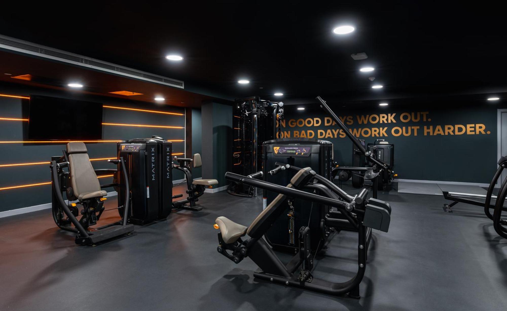 Citysuites 2 Aparthotel Manchester Bagian luar foto The photo shows a modern gym interior. The gym features various exercise machines, including weight training equipment. The flooring is dark, and the walls are adorned with motivational text that reads, "ON GOOD DAYS WORK OUT. ON BAD DAYS WORK OUT HA